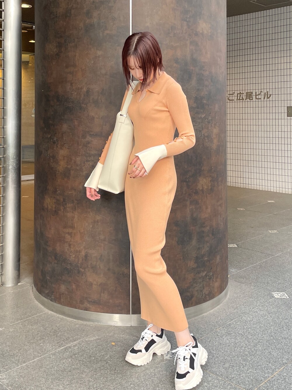 オレンジ系のワンピース、ホワイト系のショルダーバッグ、ブラック系のスニーカーを着用したレディースの冬コーディネートの1枚目の写真