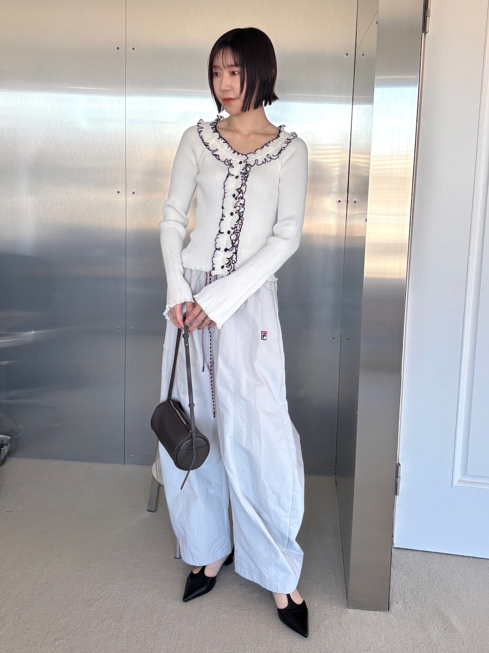 ベージュ系のその他パンツ、ホワイト系のニット/セーター、ブラック系のパンプスを着用したレディースの春コーディネートの1枚目の写真