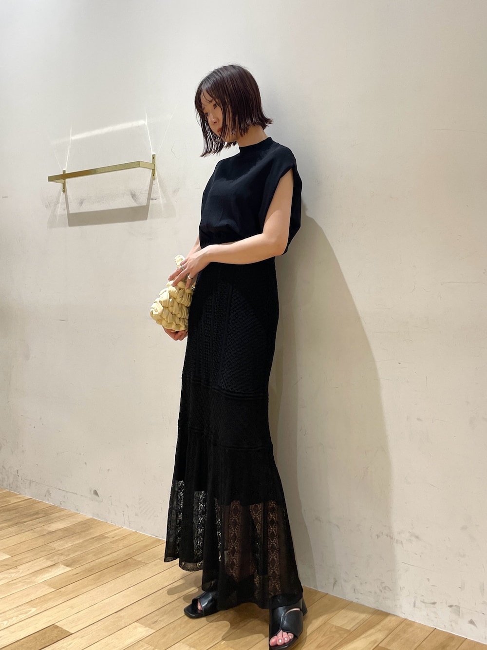 ベージュ系のハンドバッグ、ブラック系のサンダル、ブラック系のニット/セーターを着用したレディースの夏コーディネートの1枚目の写真