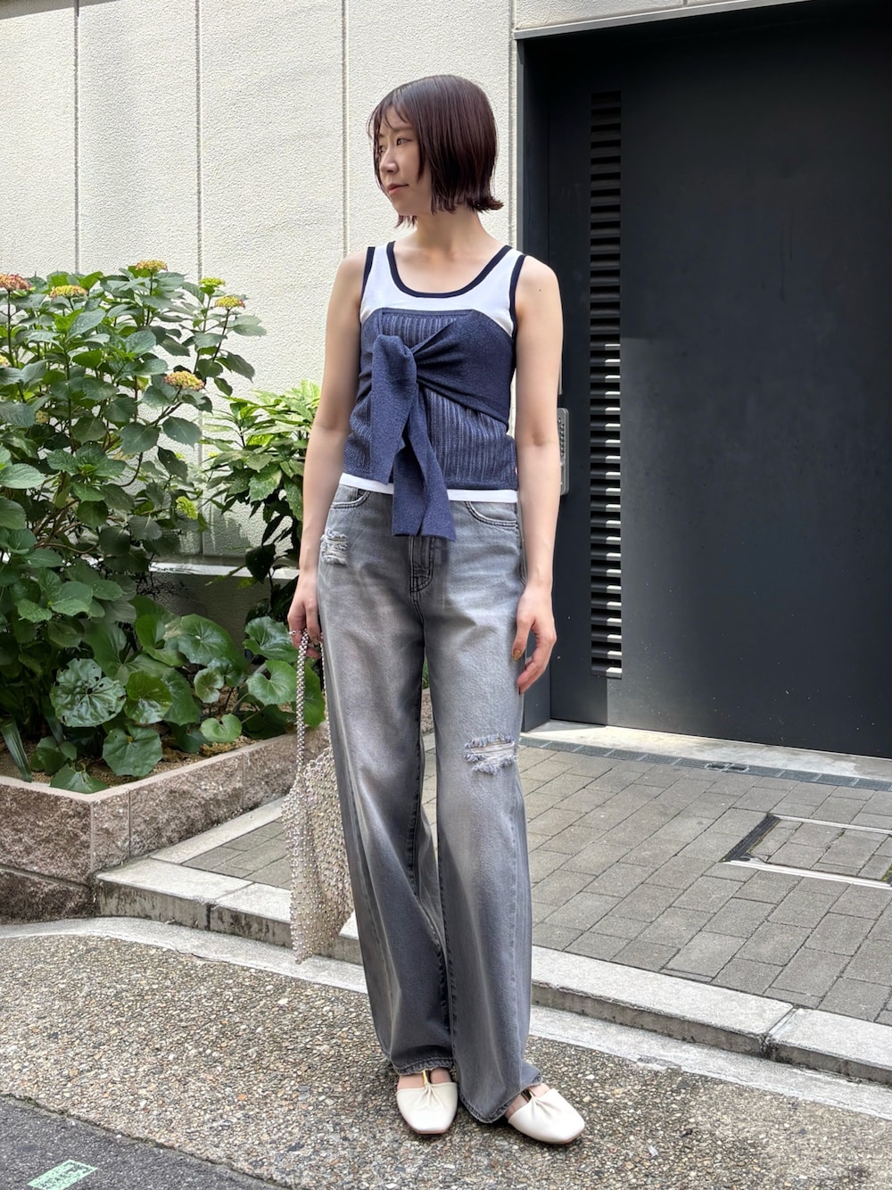 グレー系のデニムパンツ、ホワイト系のニット/セーター、ホワイト系のハンドバッグを着用したレディースの春コーディネートの1枚目の写真