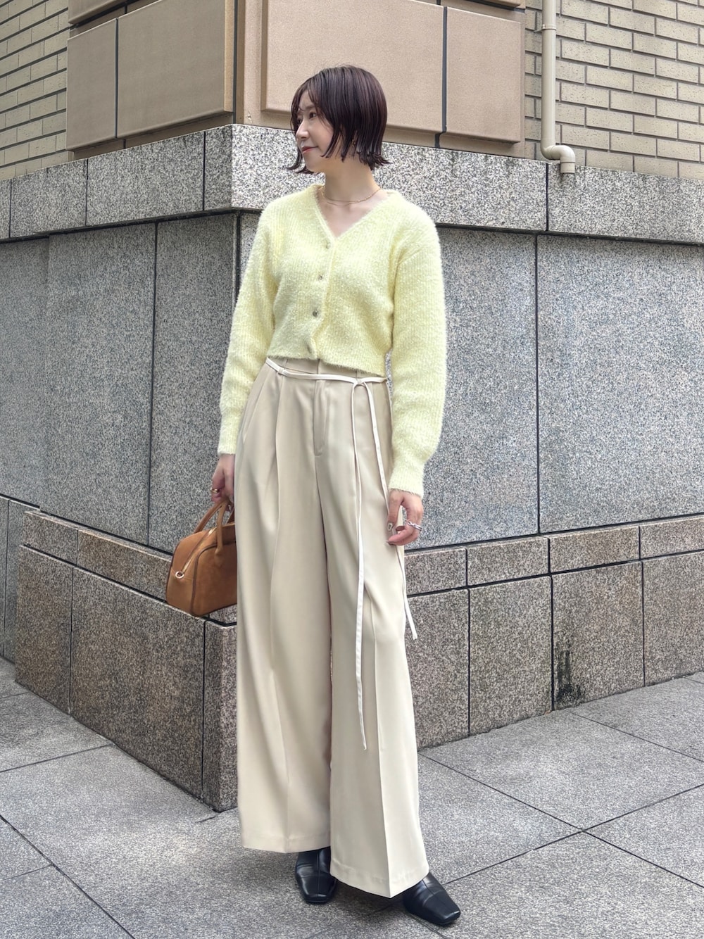 ベージュ系のその他パンツ、イエロー系のカーディガン/ボレロ、イエロー系のハンドバッグを着用したレディースの秋コーディネートの1枚目の写真