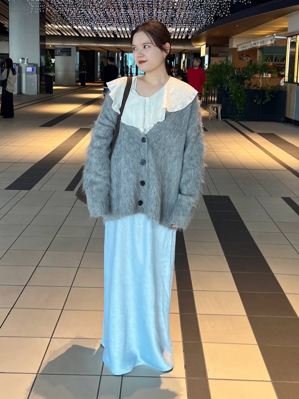 ブルー系のスカート、グレー系のカーディガン/ボレロを着用したレディースの秋コーディネートの1枚目の写真