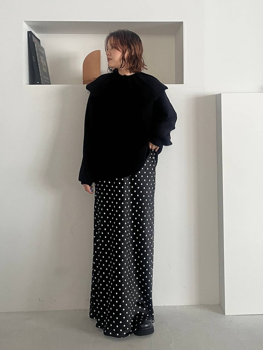 ブラック系のスカート、ブラック系のサンダル、ブラック系のニット/セーターを着用したレディースの秋コーディネートの1枚目の写真