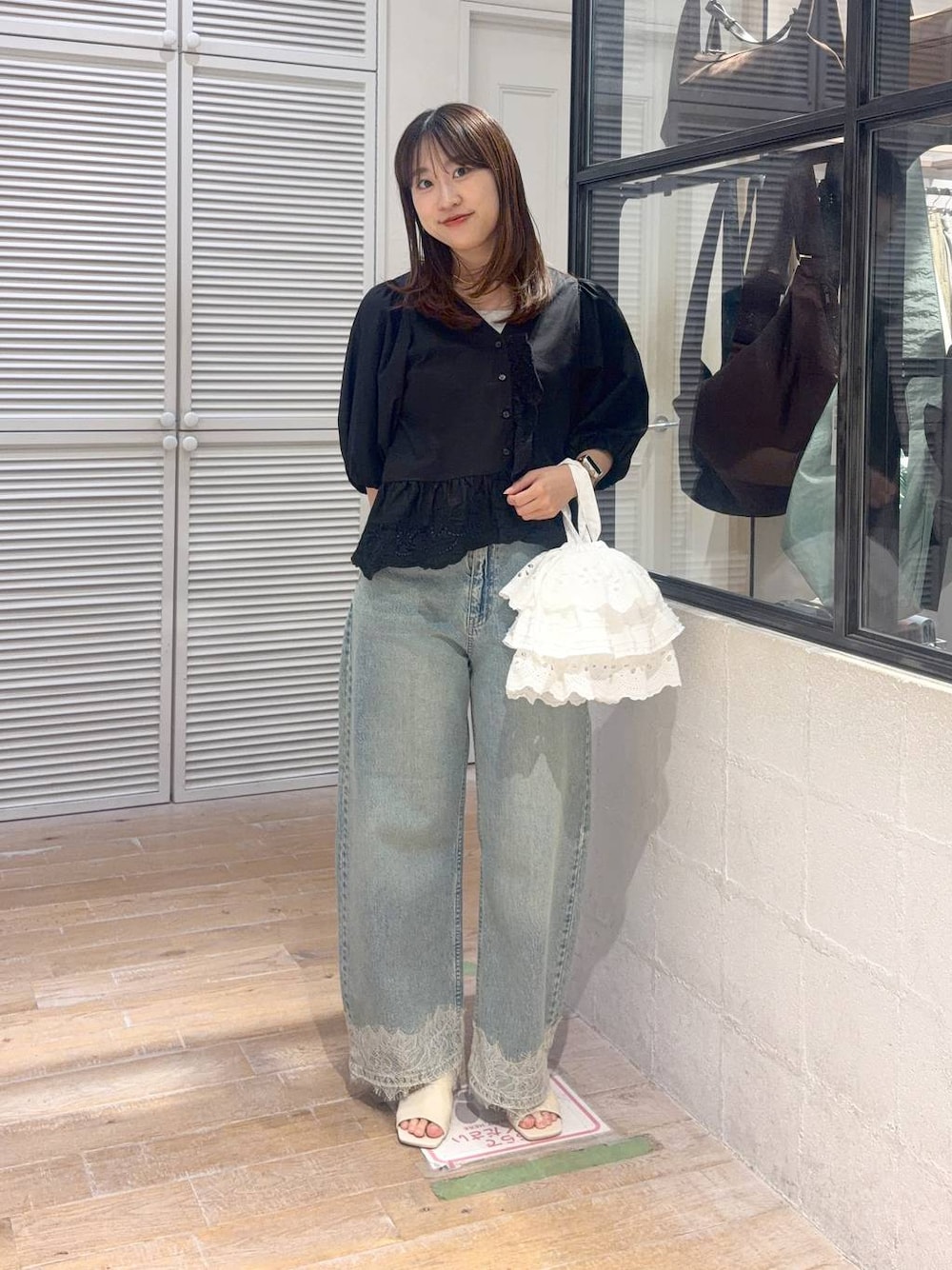 ブルー系のデニムパンツ、ブラック系のシャツ/ブラウス、ホワイト系のハンドバッグを着用したレディースの夏コーディネートの1枚目の写真