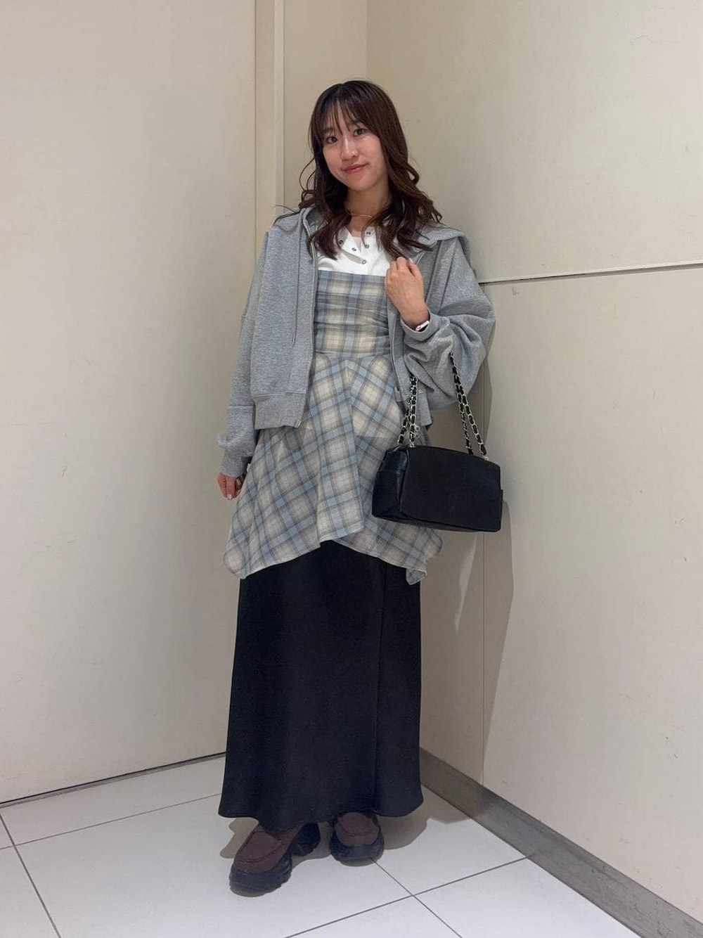ブラック系のスカート、ホワイト系のニット/セーター、グレー系のパーカーを着用したレディースの春コーディネートの1枚目の写真