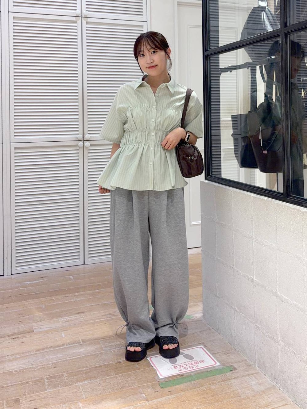 グレー系のスウェットパンツ、ブラック系のサンダル、グリーン系のTシャツ/カットソーを着用したレディースの夏コーディネートの1枚目の写真