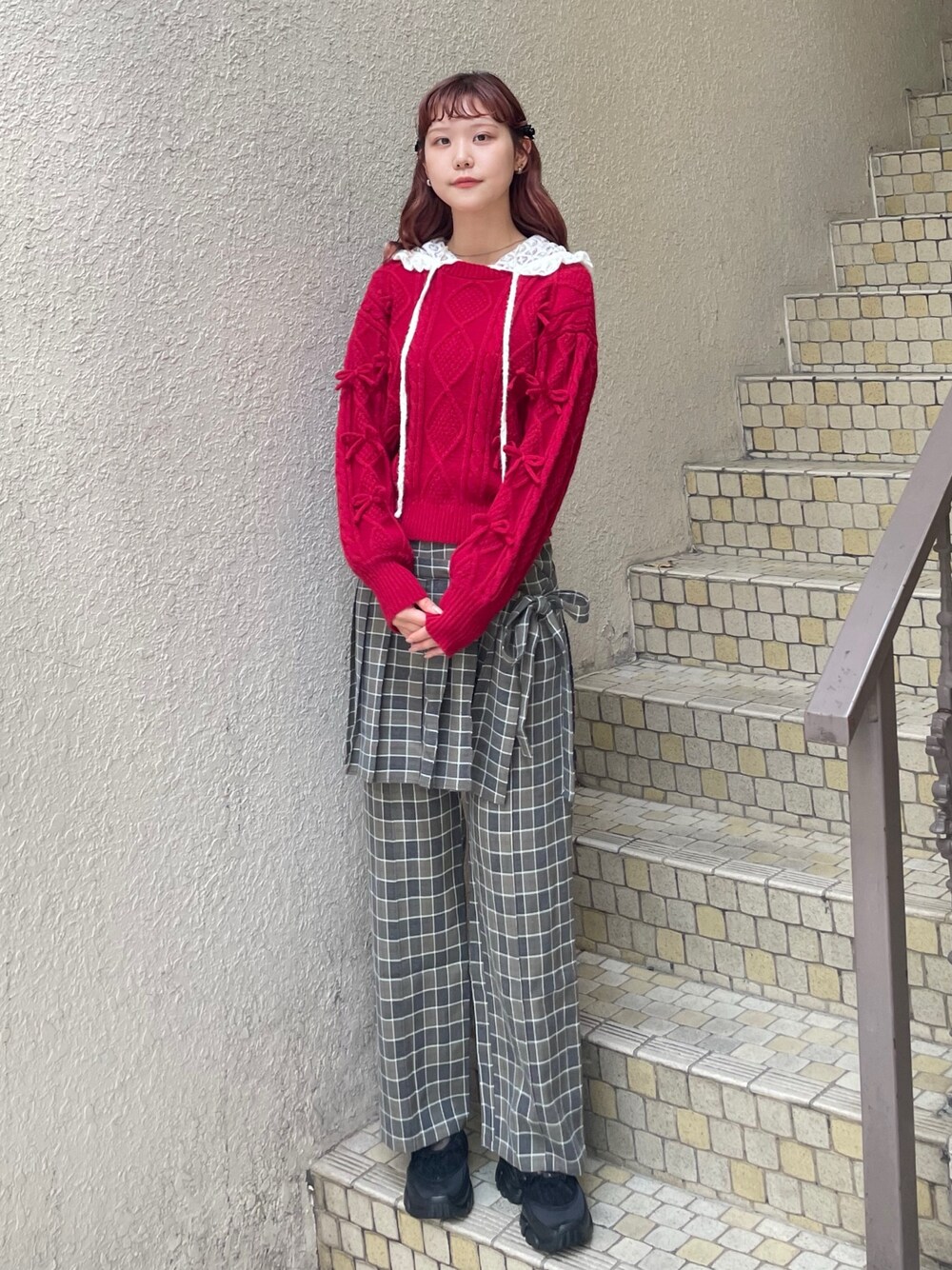 レッド系のニット/セーター、グリーン系のスラックス、ホワイト系のTシャツ/カットソーを着用したレディースの秋コーディネートの1枚目の写真