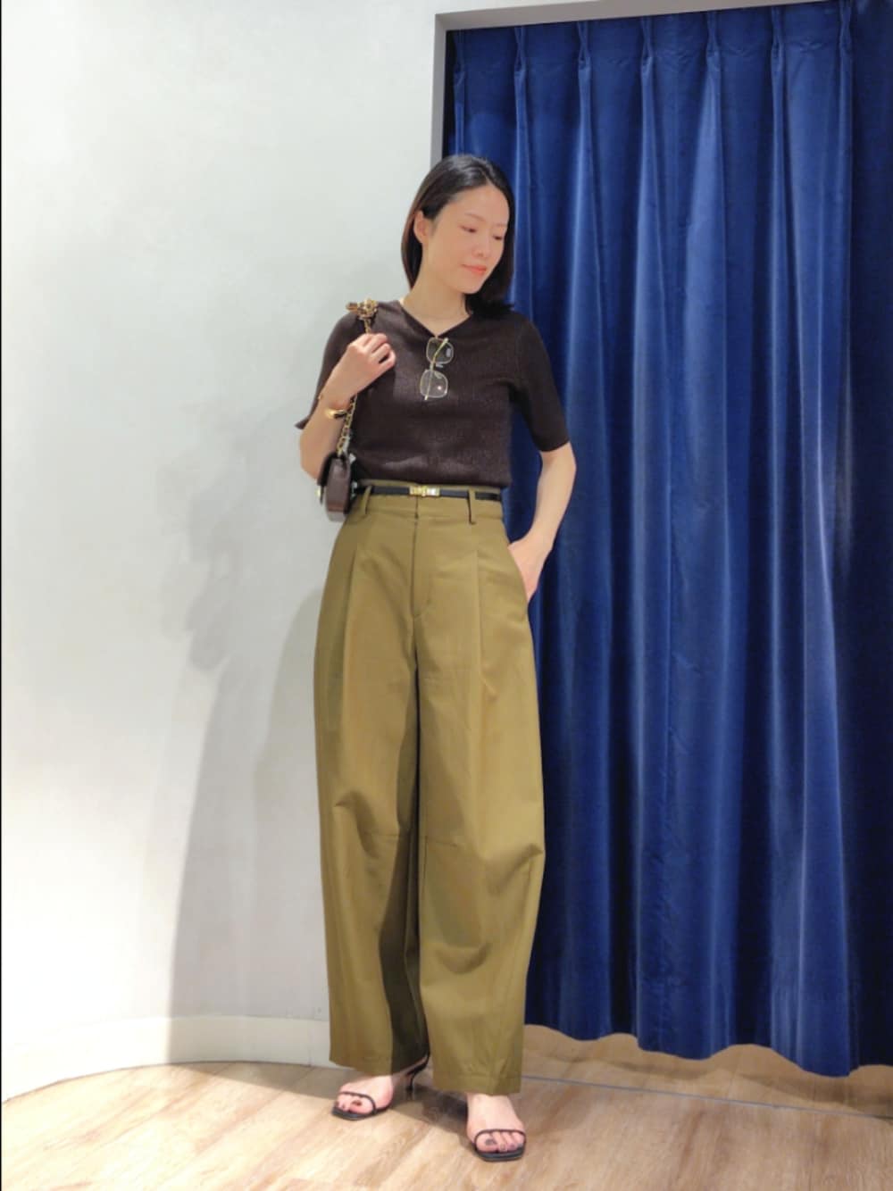 グリーン系のチノパンツ、ブラウン系のニット/セーター、ブラウン系のショルダーバッグを着用したレディースの秋コーディネートの1枚目の写真