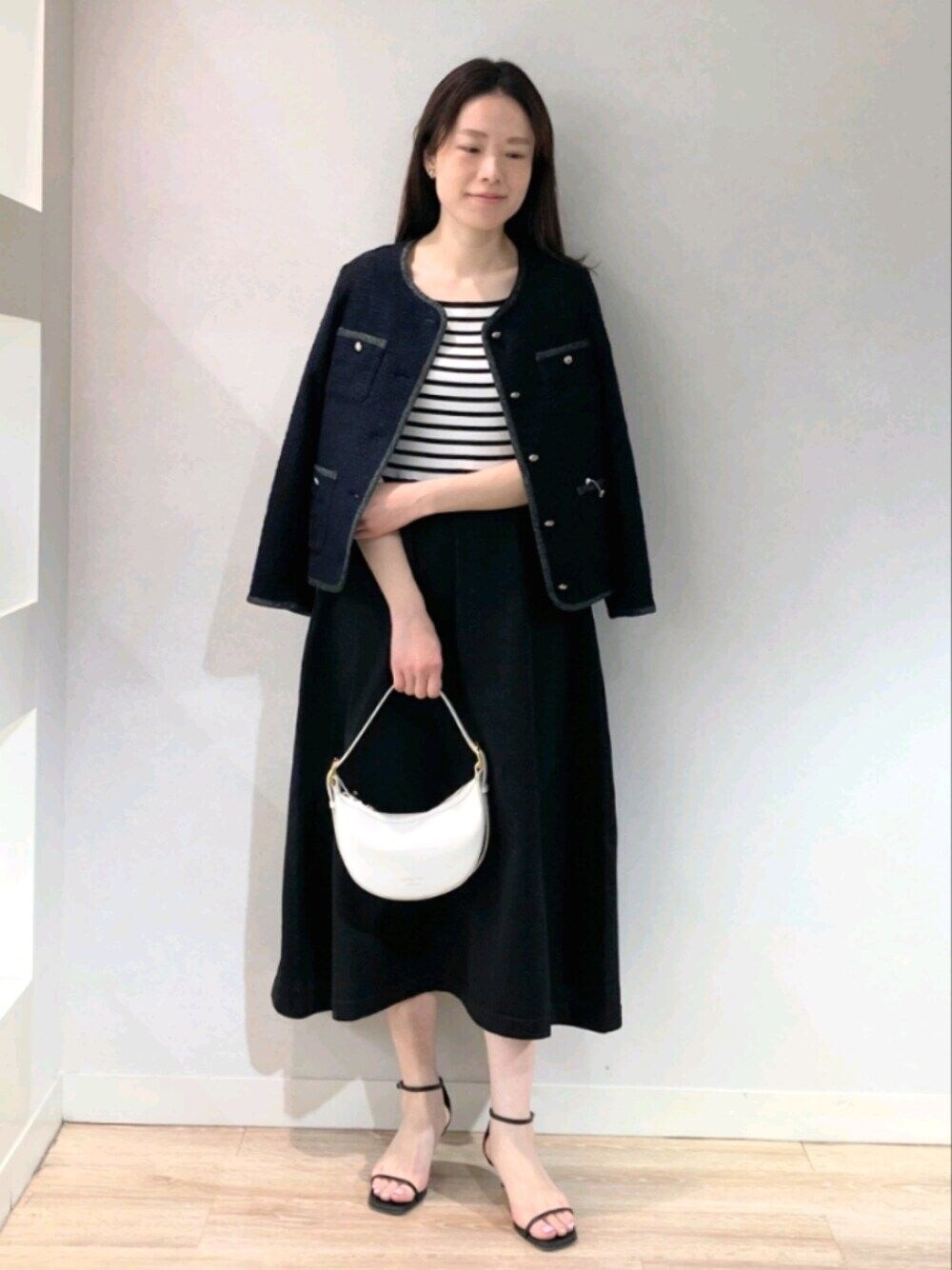 ブルー系のノーカラージャケット、ブラック系のワンピース、ホワイト系のショルダーバッグを着用したレディースの春コーディネートの1枚目の写真