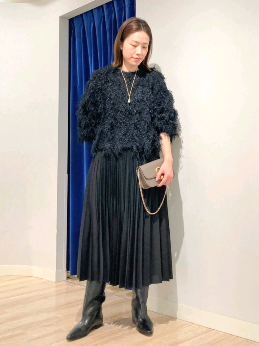 ブラック系のニット/セーター、グレー系のバッグ、ホワイト系のダウンジャケット/コートを着用したレディースの秋コーディネートの1枚目の写真