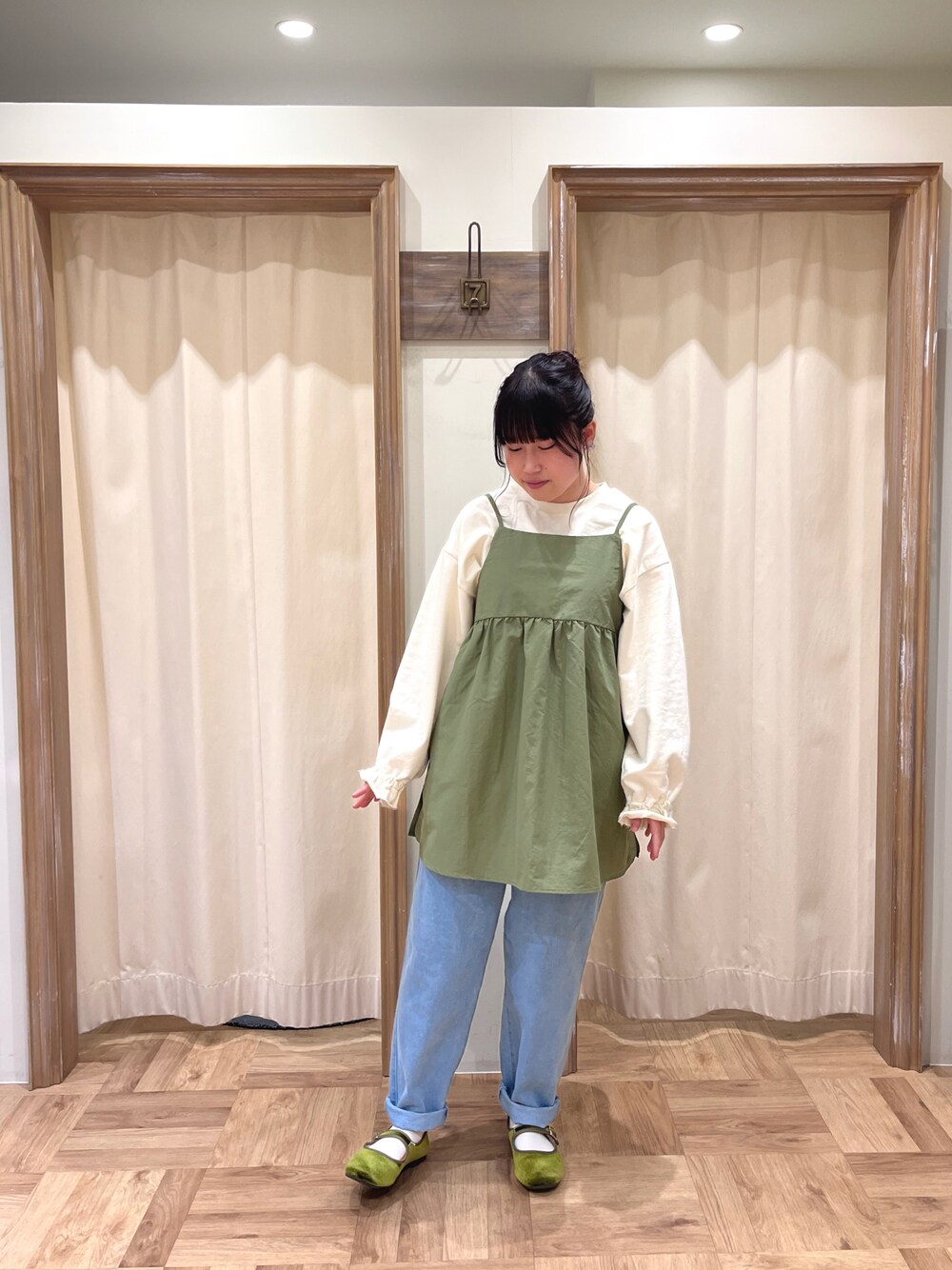 ブルー系のデニムパンツ、グリーン系のトップス、ホワイト系のスウェットを着用したレディースの春コーディネートの1枚目の写真