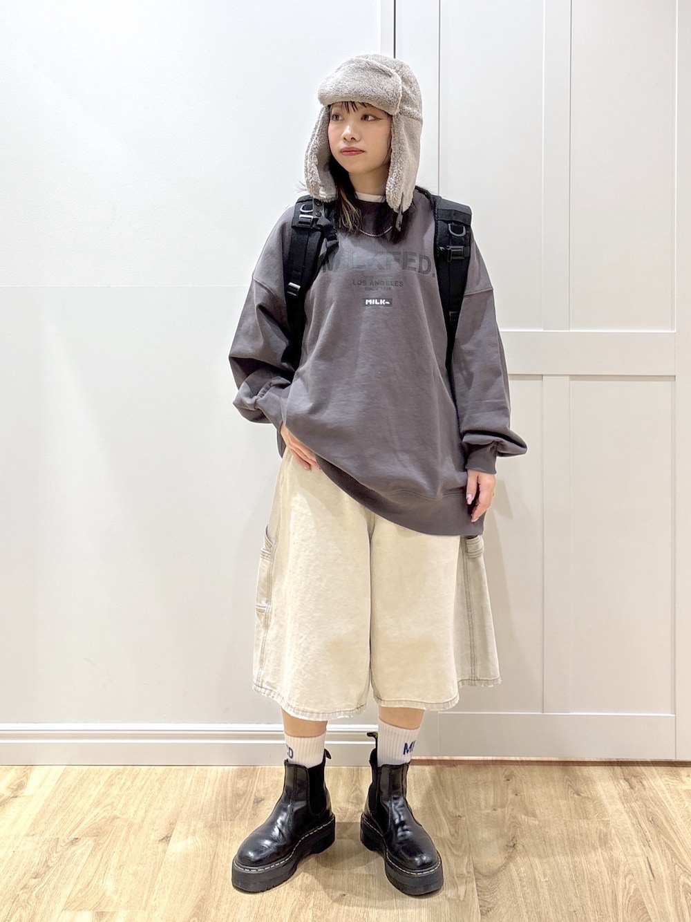 ホワイト系のデニムパンツ、グレー系のスウェット、ブラック系のバックパック/リュックを着用したレディースの冬コーディネートの1枚目の写真