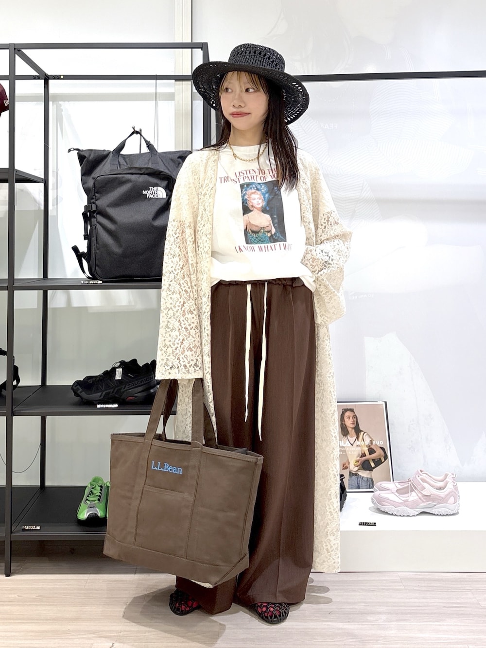 ブラウン系のトートバッグ、ブラウン系のサンダル、ホワイト系のTシャツ/カットソーを着用したレディースの春コーディネートの1枚目の写真