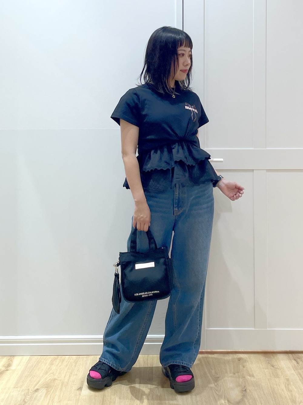 ピンク系のショルダーバッグ、ブルー系のデニムパンツ、ブラック系のサンダルを着用したレディースの夏コーディネートの1枚目の写真