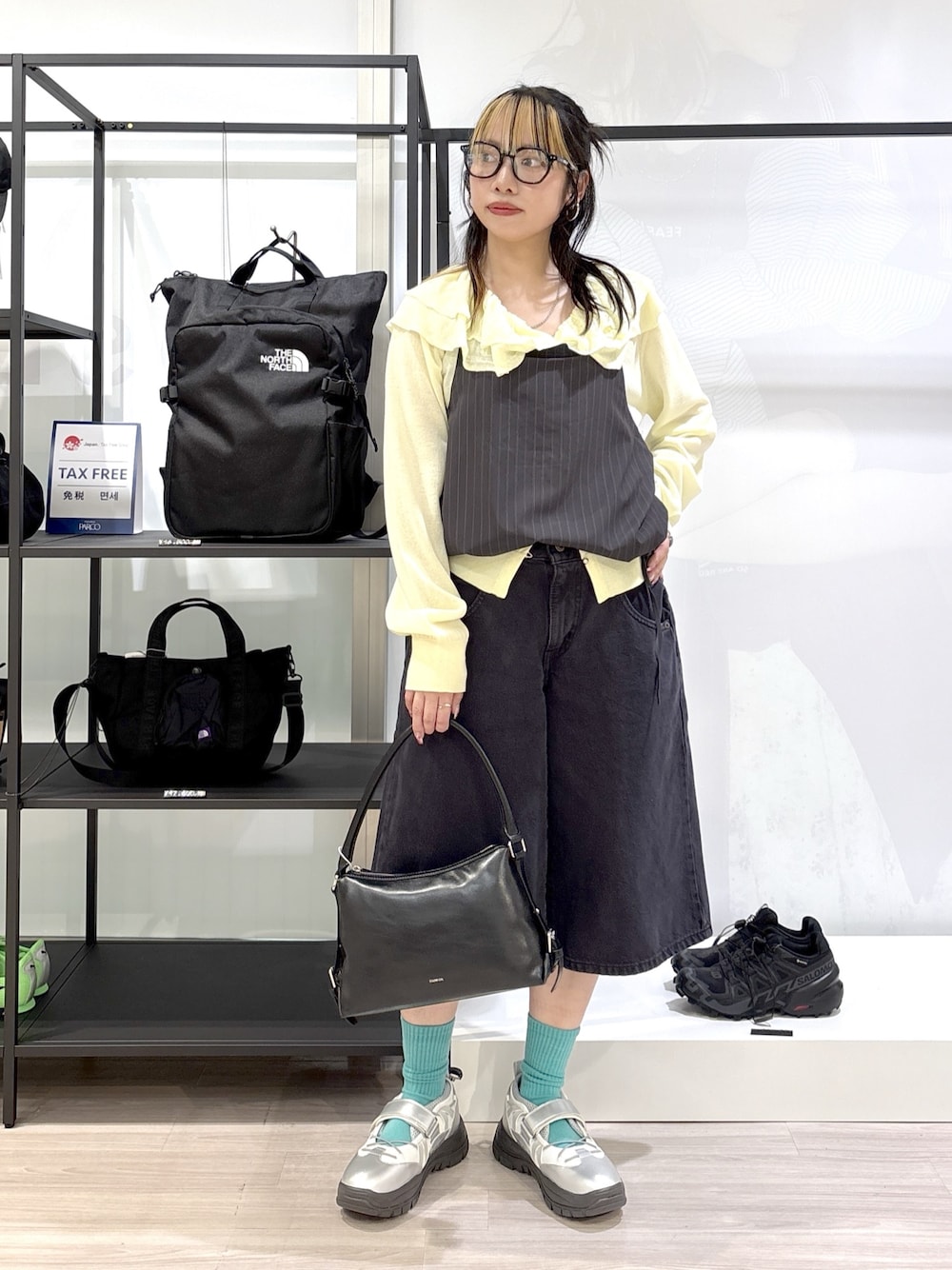シルバー系のスニーカー、ブラック系のハンドバッグ、ブラック系のデニムパンツを着用したレディースの春コーディネートの1枚目の写真