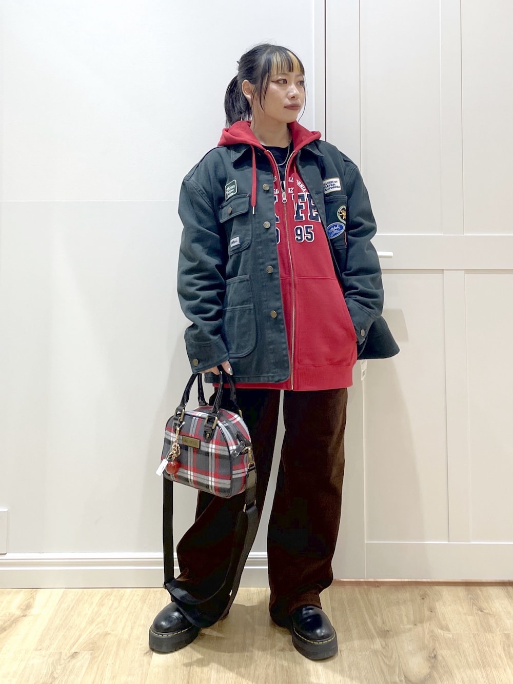 ブラック系のTシャツ/カットソー、レッド系のパーカー、ブラック系のブルゾンを着用したレディースの秋コーディネートの1枚目の写真