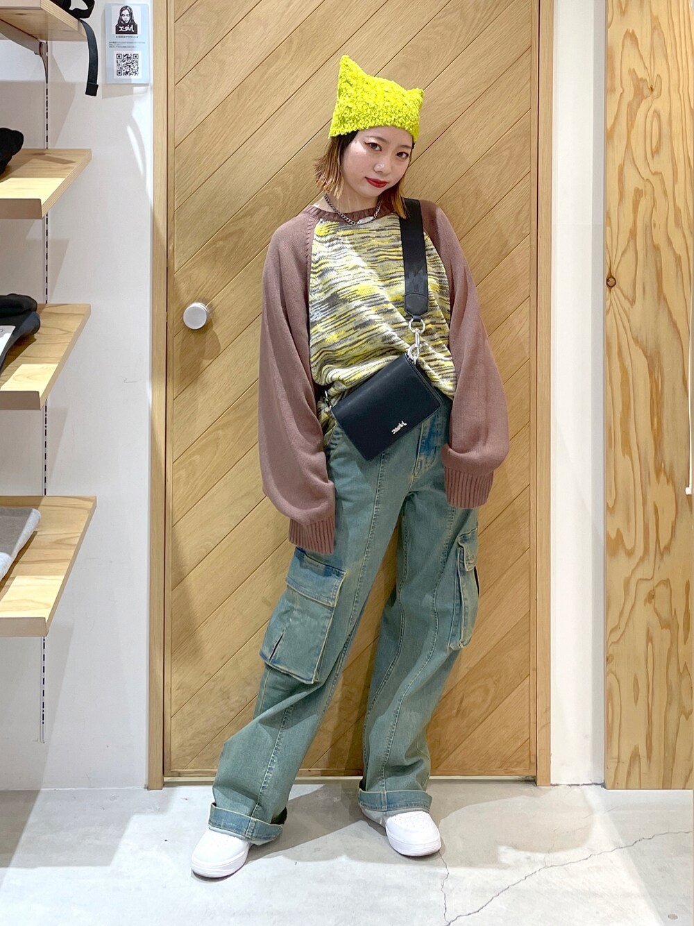 イエロー系のニット/セーター、ブルー系のカーゴパンツ、ホワイト系のスニーカーを着用したレディースの秋コーディネートの1枚目の写真