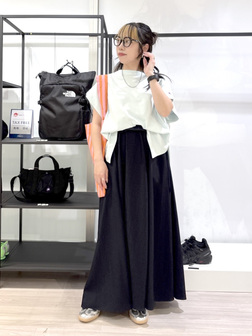 ブルー系のスカート、グリーン系のTシャツ/カットソー、シルバー系のスニーカーを着用したレディースの春コーディネートの1枚目の写真