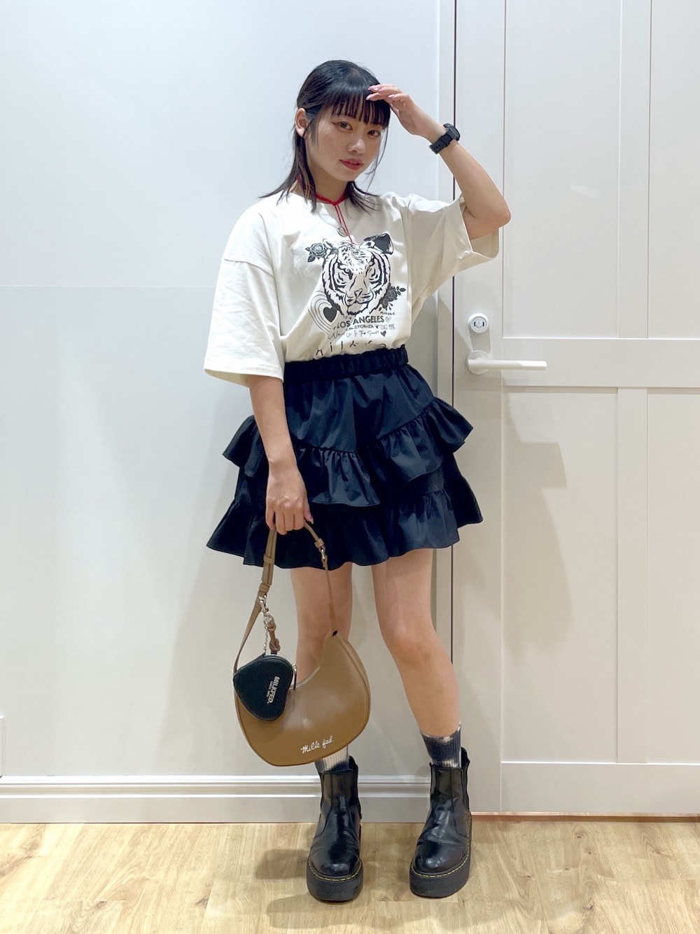 ブラック系のスカート、ホワイト系のTシャツ/カットソー、ブラック系のブーツを着用したレディースの夏コーディネートの1枚目の写真