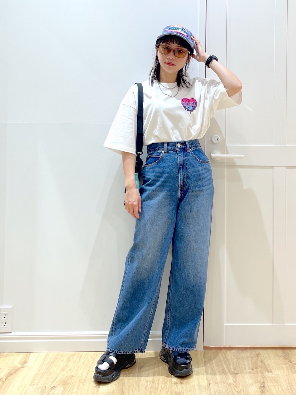 グリーン系のショルダーバッグ、ブラック系のサンダル、ホワイト系のTシャツ/カットソーを着用したレディースの夏コーディネートの1枚目の写真