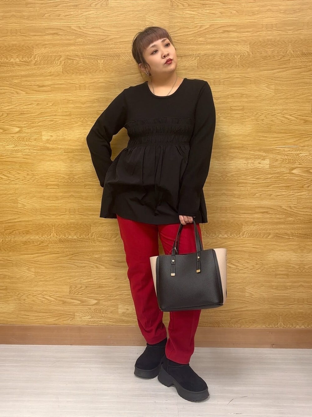 ブラック系のチュニック、レッド系のその他パンツ、ブラック系のブーツを着用したレディースの冬コーディネートの1枚目の写真