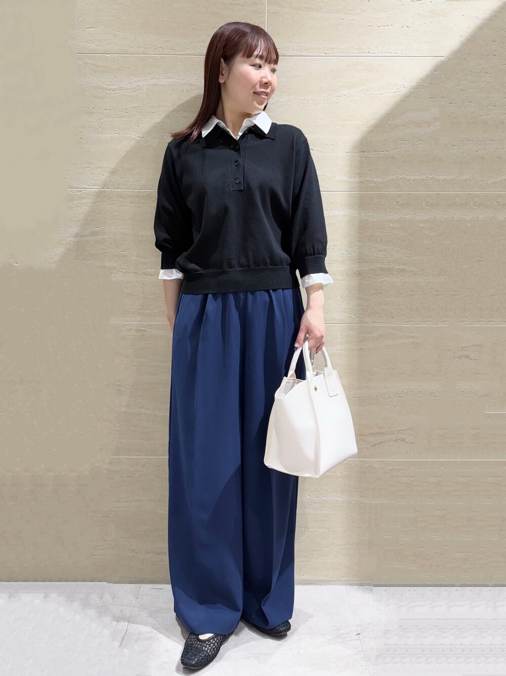 ブラック系のニット/セーター、ブルー系のその他パンツ、ホワイト系のショルダーバッグを着用したレディースの春コーディネートの1枚目の写真