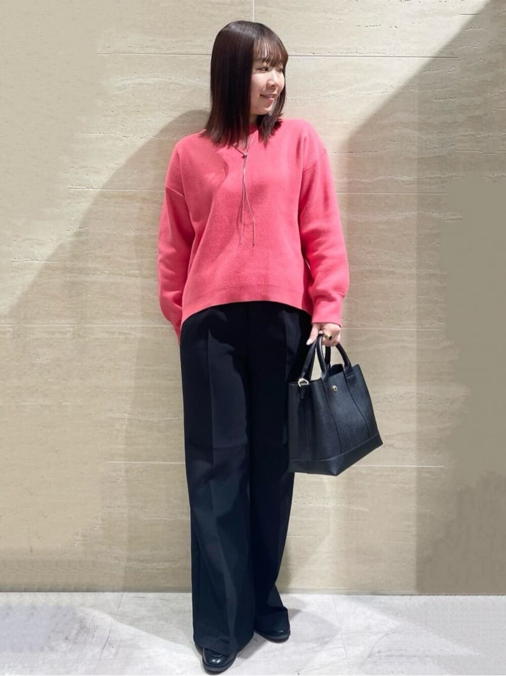ピンク系のニット/セーター、ブラック系のその他パンツ、ブラック系のトートバッグを着用したレディースの冬コーディネートの1枚目の写真