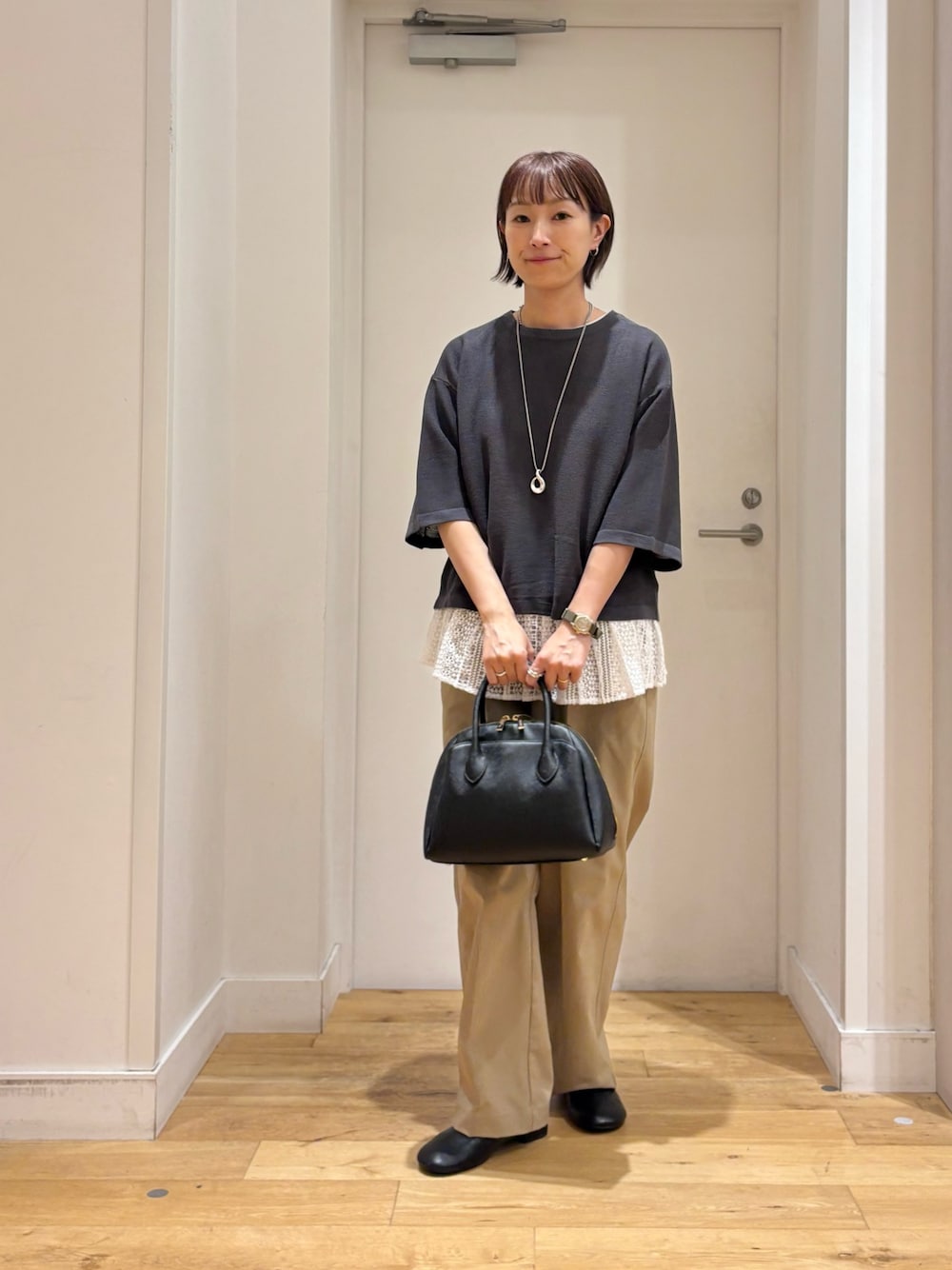 グレー系のニット/セーター、ベージュ系のその他パンツ、ブラック系のハンドバッグを着用したレディースの秋コーディネートの1枚目の写真