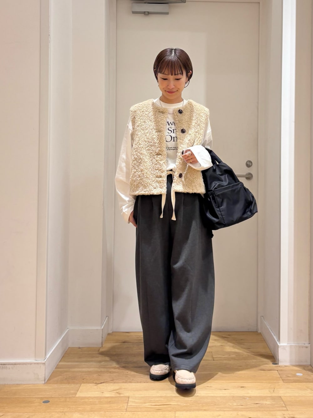 ベージュ系のダウンベスト、グレー系のその他パンツ、ホワイト系のTシャツ/カットソーを着用したレディースの秋コーディネートの1枚目の写真