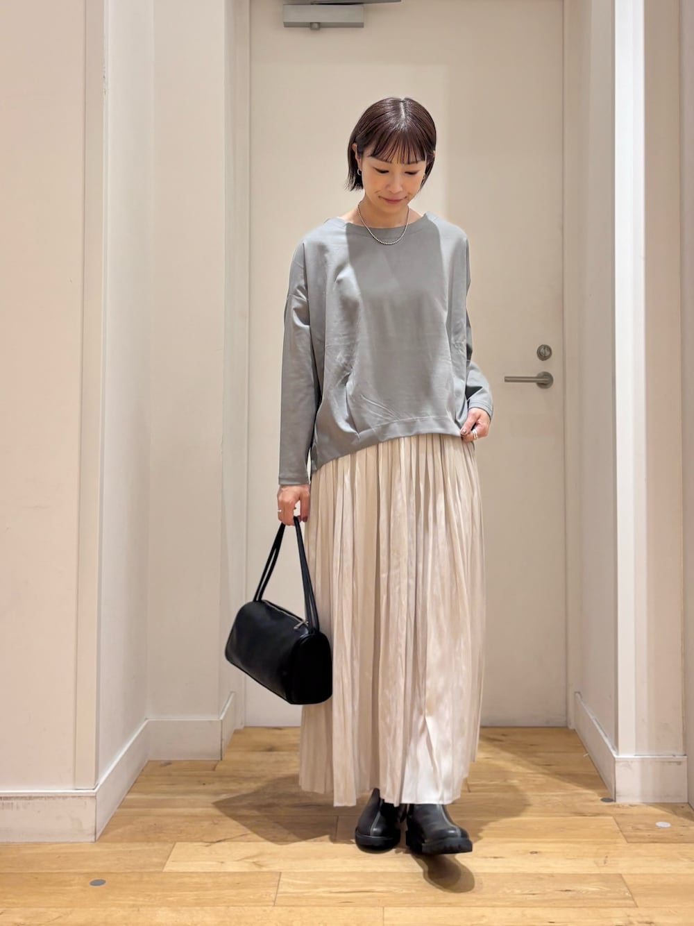 ブルー系のTシャツ/カットソー、ブラック系のハンドバッグ、ブラック系のレインシューズを着用したレディースの秋コーディネートの1枚目の写真
