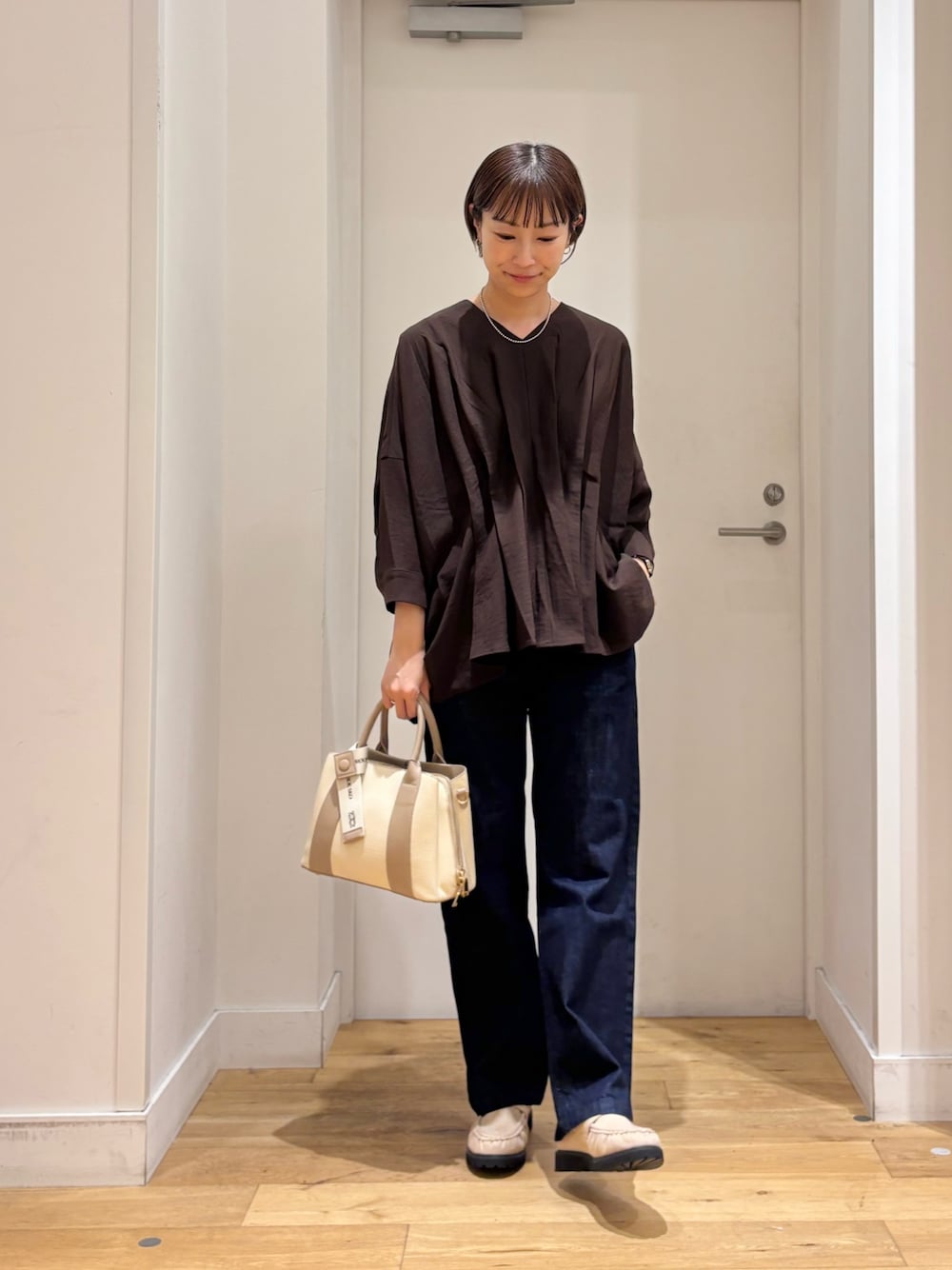 ブラウン系のシャツ/ブラウス、ブルー系のデニムパンツ、ホワイト系のハンドバッグを着用したレディースの秋コーディネートの1枚目の写真