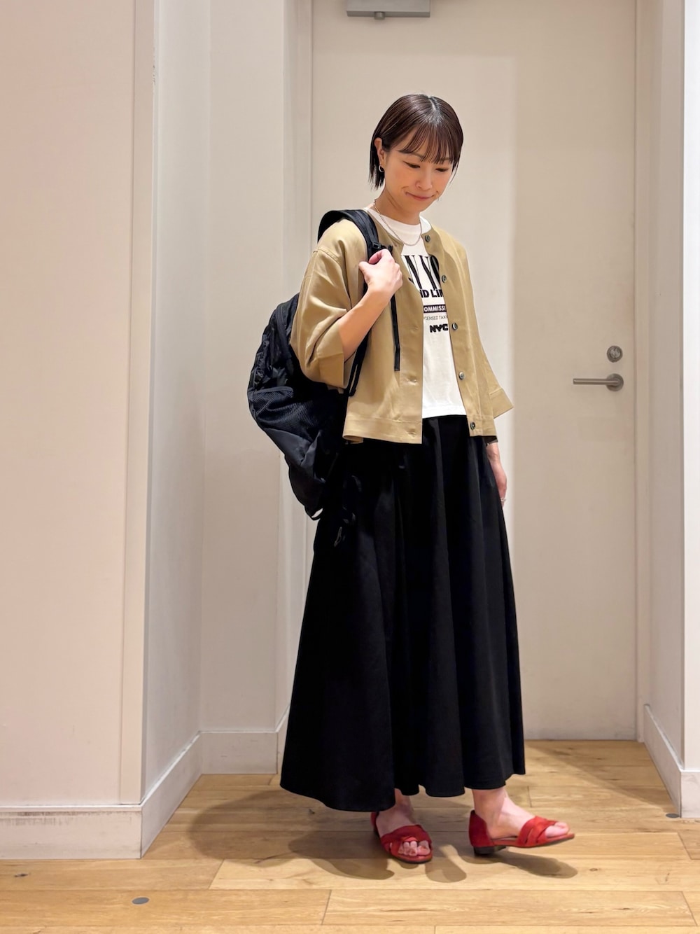 ベージュ系のシャツ/ブラウス、ブラック系のスカート、ホワイト系のTシャツ/カットソーを着用したレディースの春コーディネートの1枚目の写真
