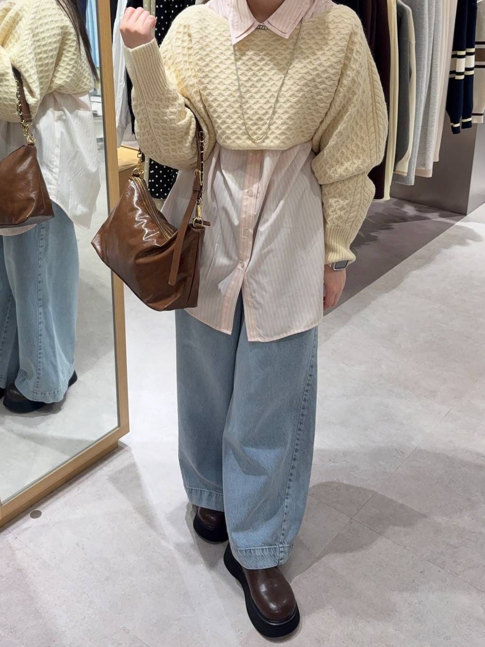 ホワイト系のニット/セーター、ブルー系のデニムパンツ、ブラウン系のショルダーバッグを着用したレディースの冬コーディネートの1枚目の写真