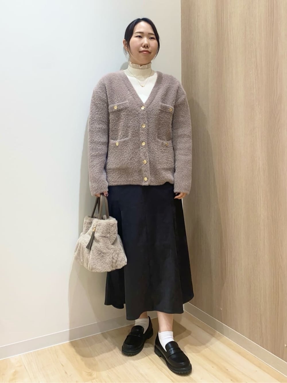 ベージュ系のカーディガン/ボレロ、ホワイト系のニット/セーター、グレー系のスカートを着用したレディースの秋コーディネートの1枚目の写真