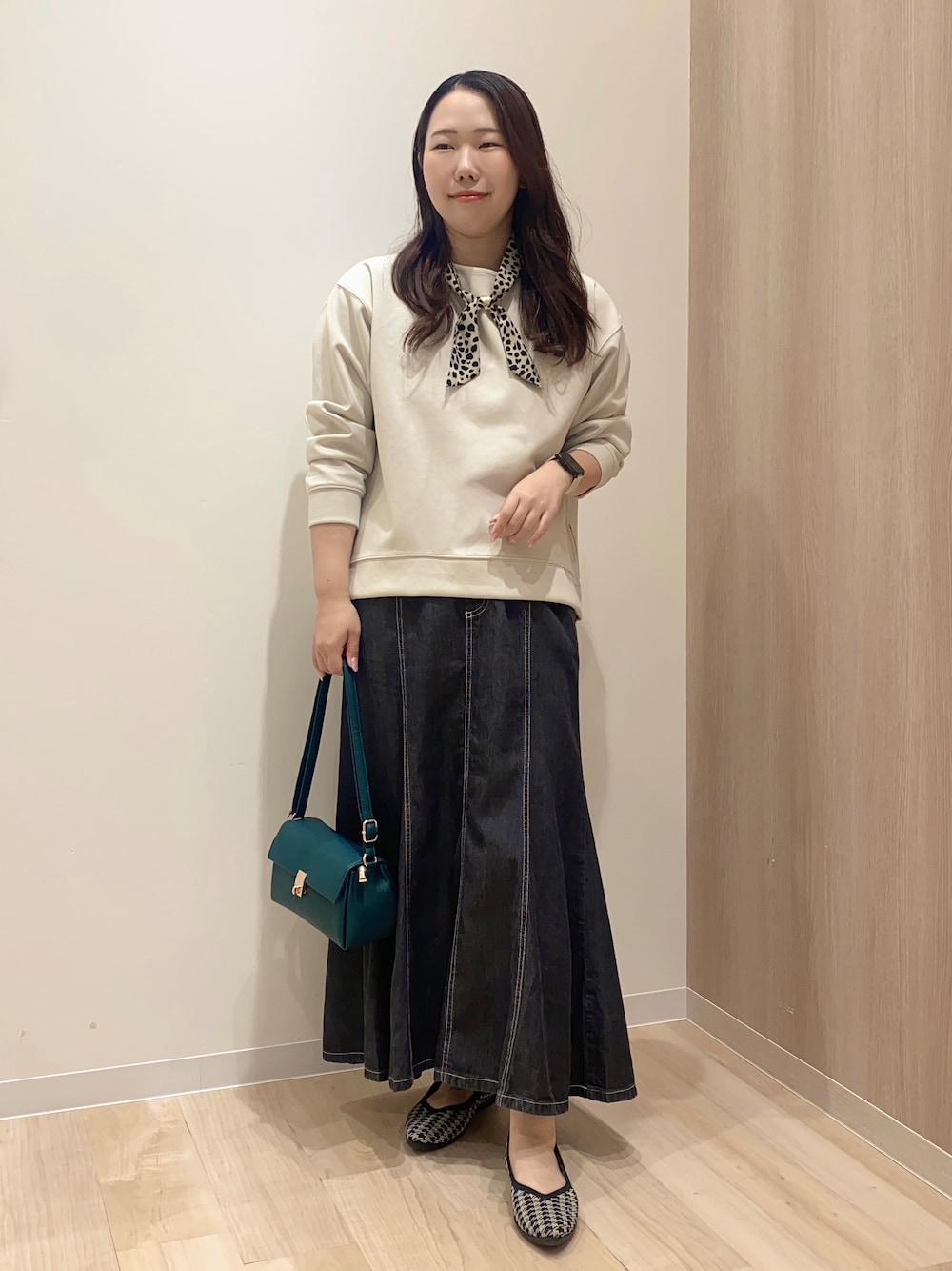 ベージュ系のTシャツ/カットソー、ブラック系のデニムスカート、グリーン系のショルダーバッグを着用したレディースの秋コーディネートの1枚目の写真