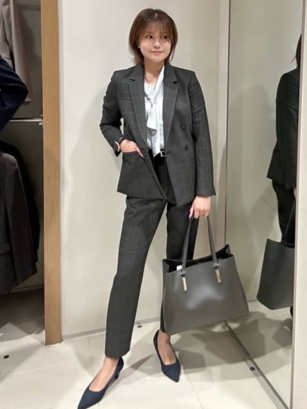 グレー系のテーラードジャケット、グレー系のスラックス、ブルー系のシャツ/ブラウスを着用したレディースの冬コーディネートの1枚目の写真