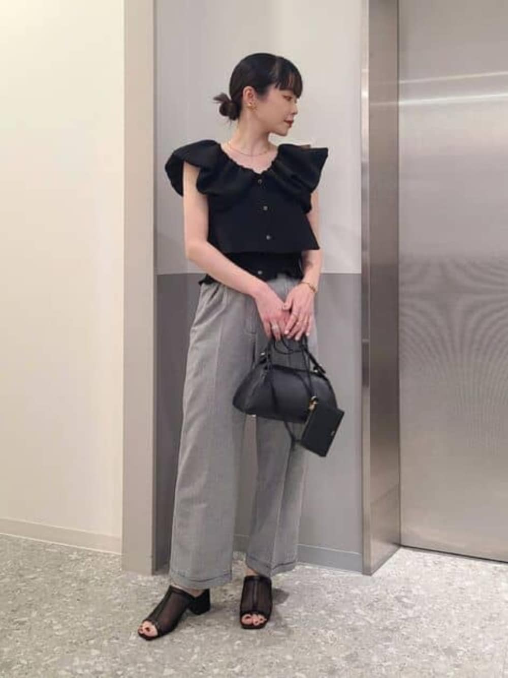 ブラック系のシャツ/ブラウス、ブラック系のスラックスを着用したレディースの春コーディネートの1枚目の写真