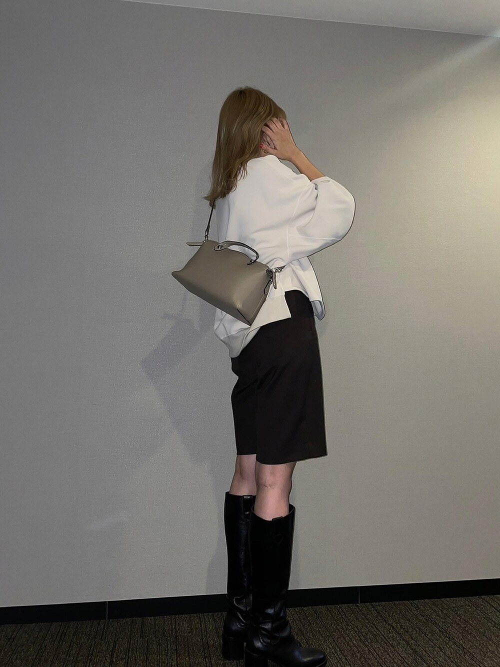 ブラック系のブーツ、ブラウン系のスラックス、ホワイト系のスウェットを着用したレディースの秋コーディネートの1枚目の写真