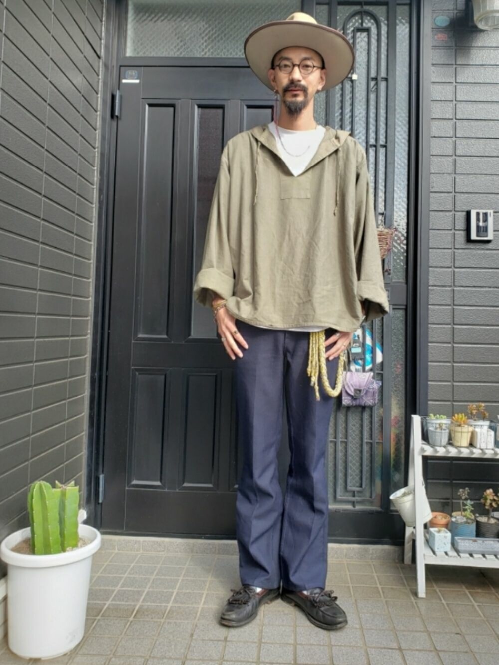 ブラック系のスラックス、ブラック系のローファー、グリーン系のトップスを着用したメンズの秋コーディネートの1枚目の写真