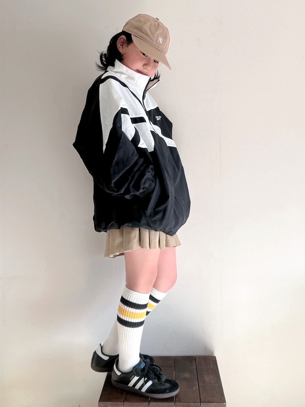「春のおしゃ見えテクニック、春服みてみて、お出かけコーデ、プリーツスカート、春アウター、トラックジャケット、リーボック(Reebok)、ラインソックス、adidas、samba、キャップ、スポーツミックス、スニーカーコーデ、休日スタイル」｜「Reebokの【Reebok/リーボック】ナイロンベクターJK/ビッグロゴナイロントラックジャケットブルゾン（ブルゾン、ブラック系）」を使った、bow-changさん（キッズ・130cm）の春コーディネートの1枚目の写真
