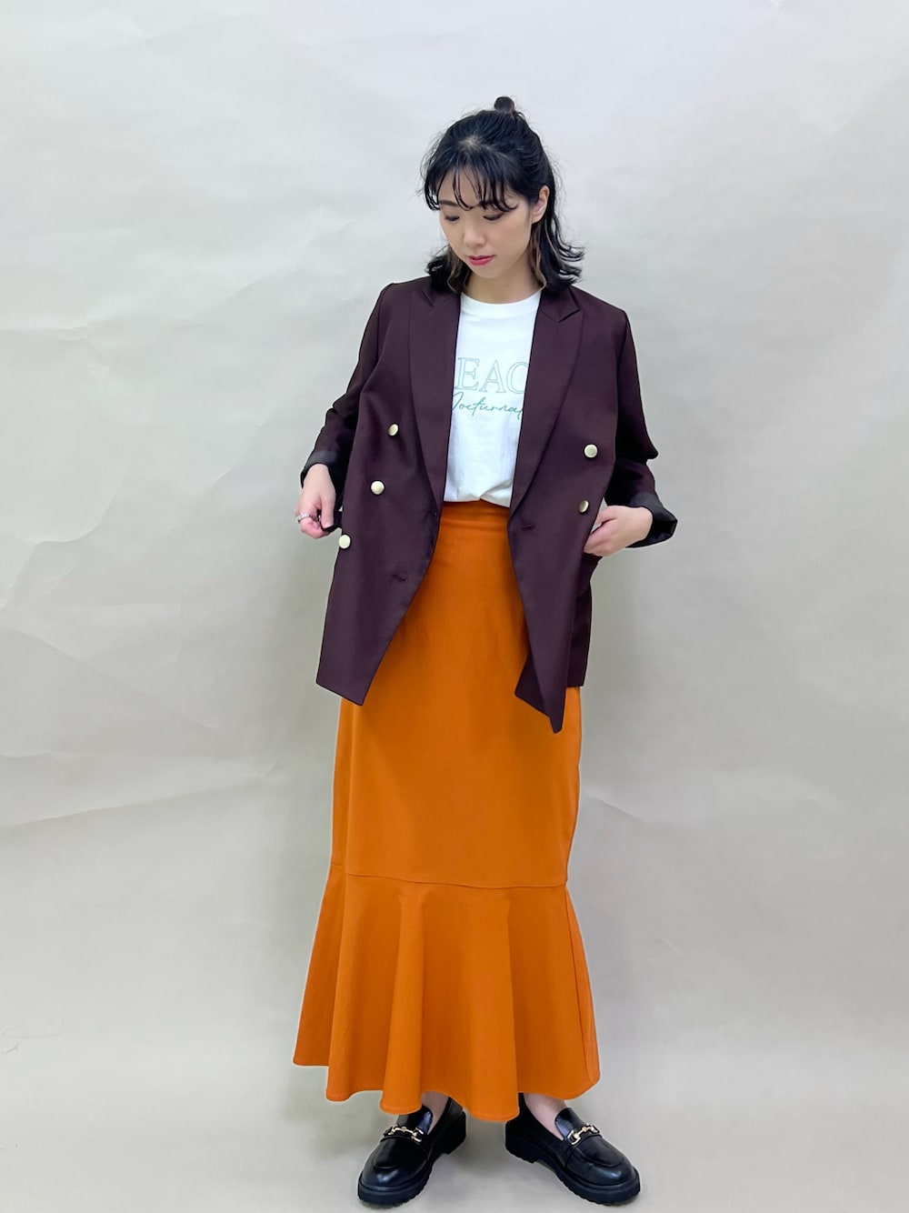 ブラウン系のその他アウター、イエロー系のスカート、グリーン系のTシャツ/カットソーを着用したレディースの秋コーディネートの1枚目の写真