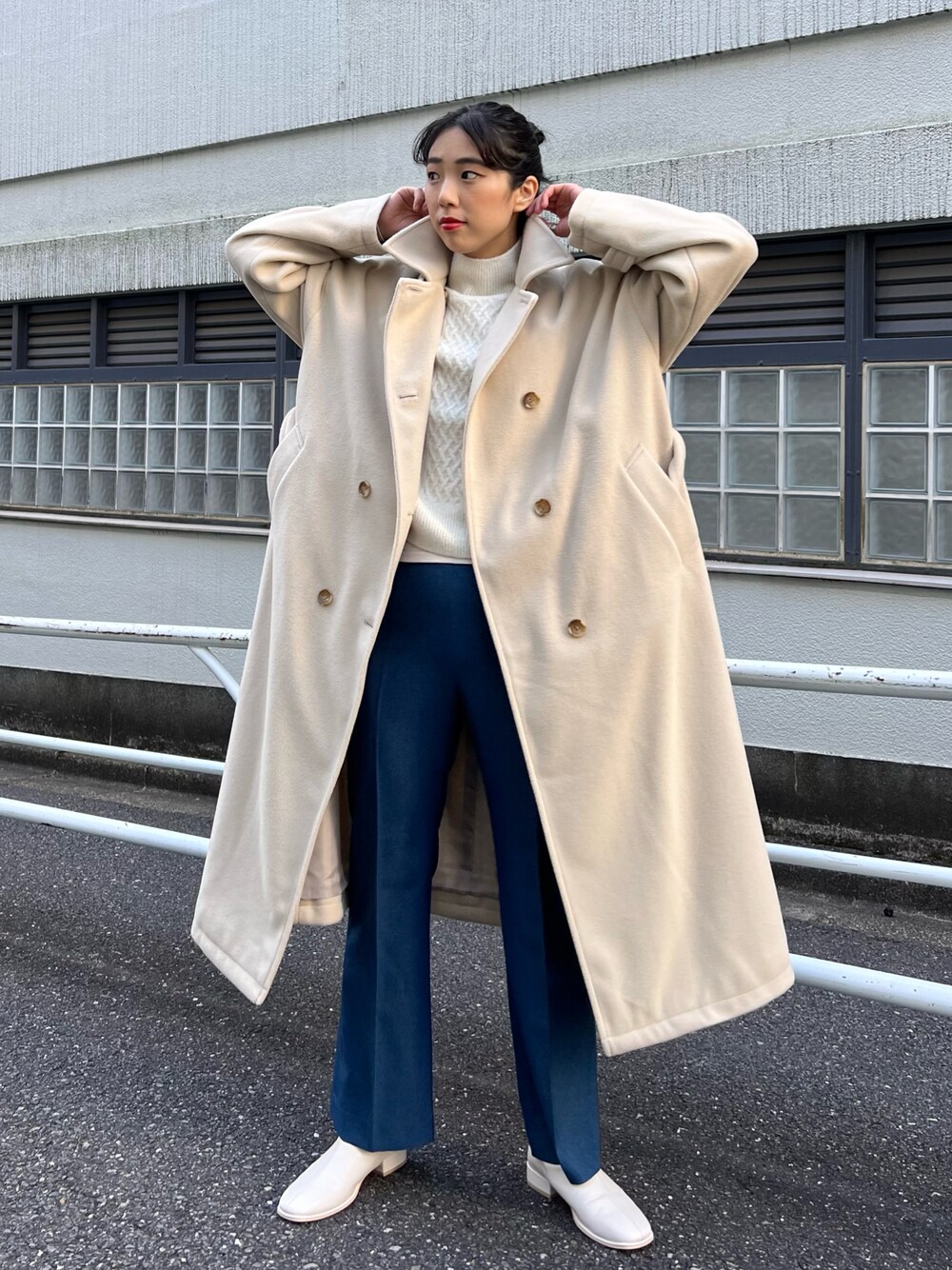 ベージュ系のステンカラーコート、ホワイト系のベスト、ホワイト系のニット/セーターを着用したレディースの秋コーディネートの1枚目の写真