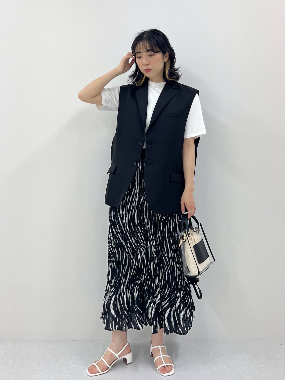 ホワイト系のTシャツ/カットソー、ブラック系のベスト、ホワイト系のサンダルを着用したレディースの春コーディネートの1枚目の写真