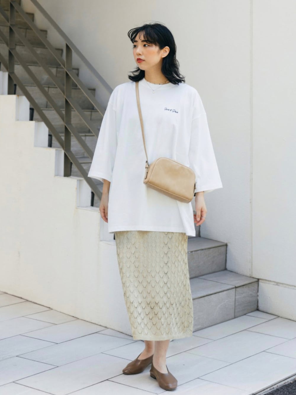 イエロー系のスカート、ベージュ系のショルダーバッグ、ホワイト系のTシャツ/カットソーを着用したレディースの夏コーディネートの1枚目の写真