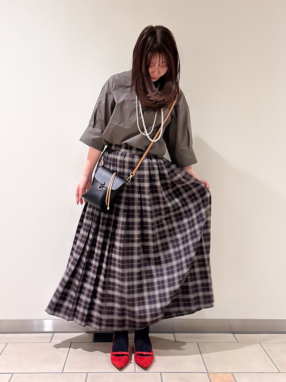 レッド系のパンプス、ブラック系のショルダーバッグ、グレー系のシャツ/ブラウスを着用したレディースの春コーディネートの1枚目の写真