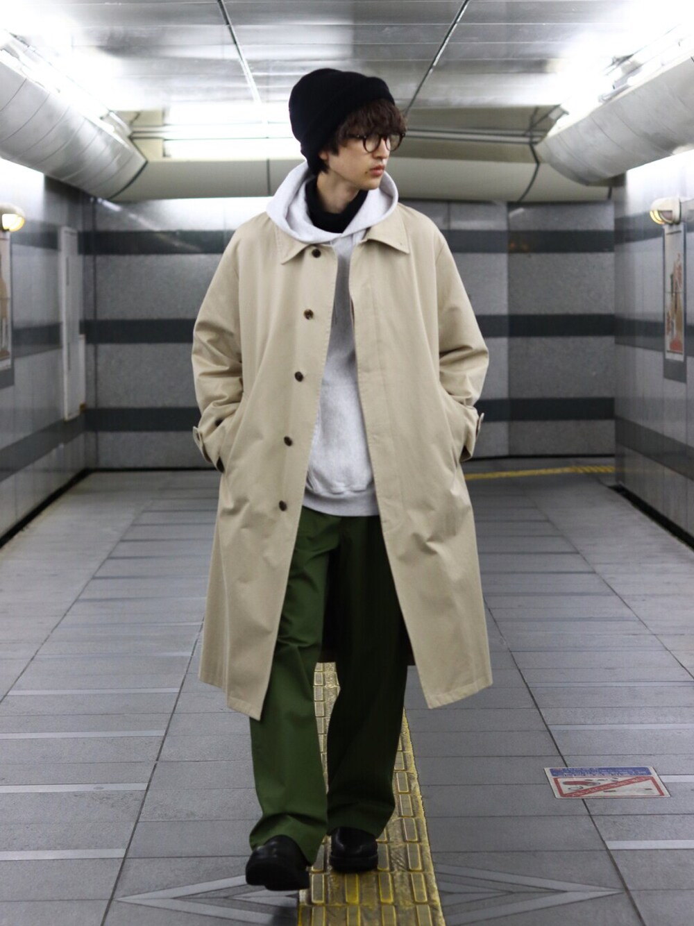 グレー系のパーカー、ベージュ系のトレンチコート、グリーン系のカーゴパンツを着用したメンズの冬コーディネートの1枚目の写真