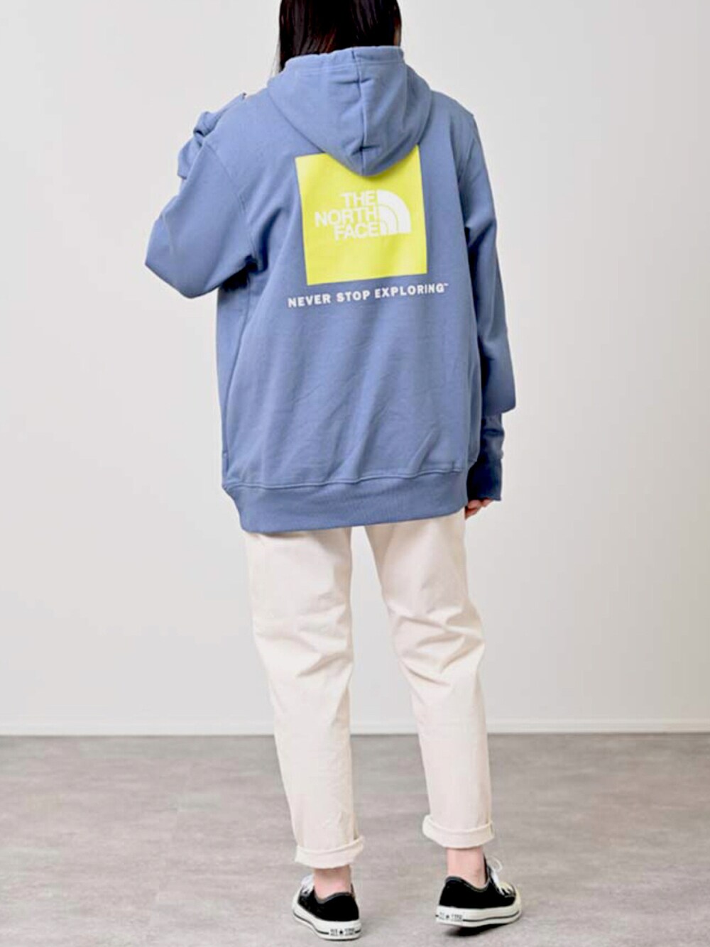 ブルー系のパーカー、ホワイト系のパンツ、ブラック系のスニーカーを着用したレディースの夏コーディネートの1枚目の写真