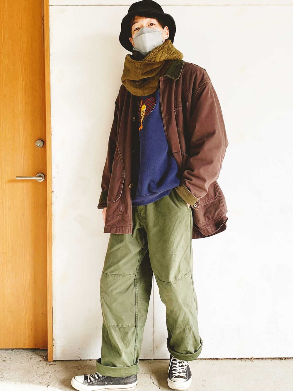 ブルー系のスウェット、ブラウン系のカバーオール、グリーン系のカーゴパンツを着用したメンズの秋コーディネートの1枚目の写真