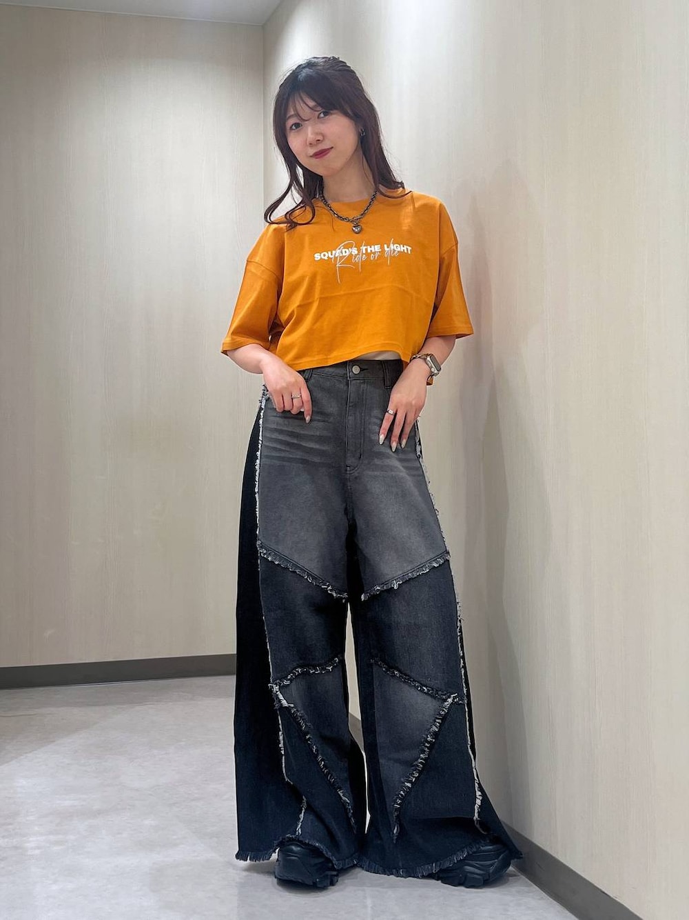ブラック系のスニーカー、オレンジ系のTシャツ/カットソー、ブラック系のデニムパンツを着用したレディースの夏コーディネートの1枚目の写真