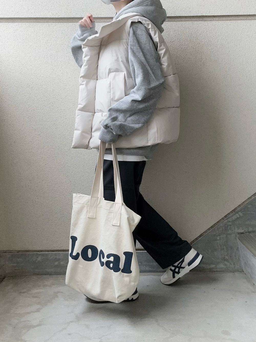 ホワイト系のダウンベスト、グレー系のスラックス、グレー系のパーカーを着用したレディースの冬コーディネートの1枚目の写真